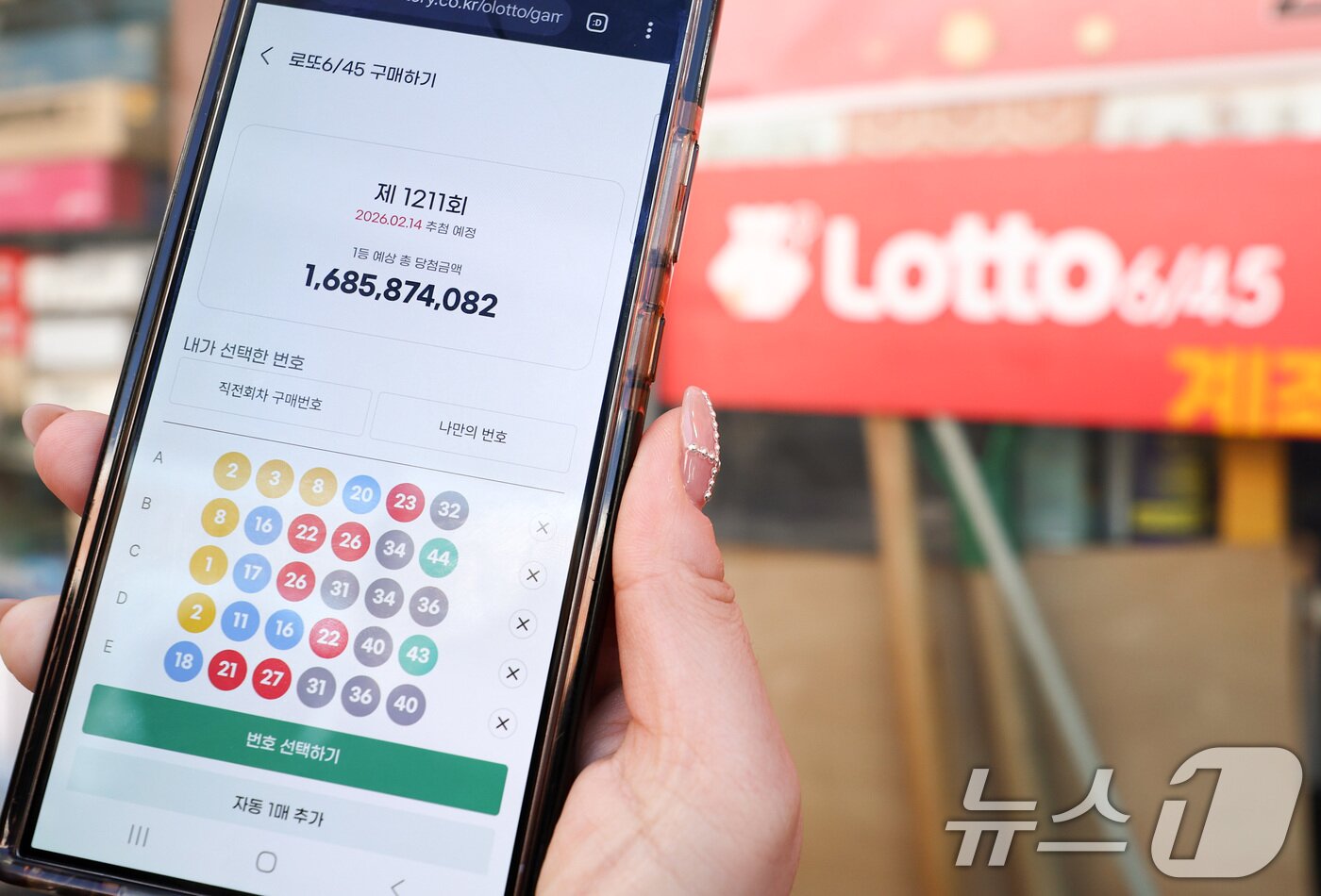 본문 이미지 - 모바일 로또 판매가 시작된 9일 서울 시내의 한 복권 판매점 앞에서 시민이 휴대폰으로 로또를 구매하고 있다. 2026.2.9 ⓒ 뉴스1 최지환 기자