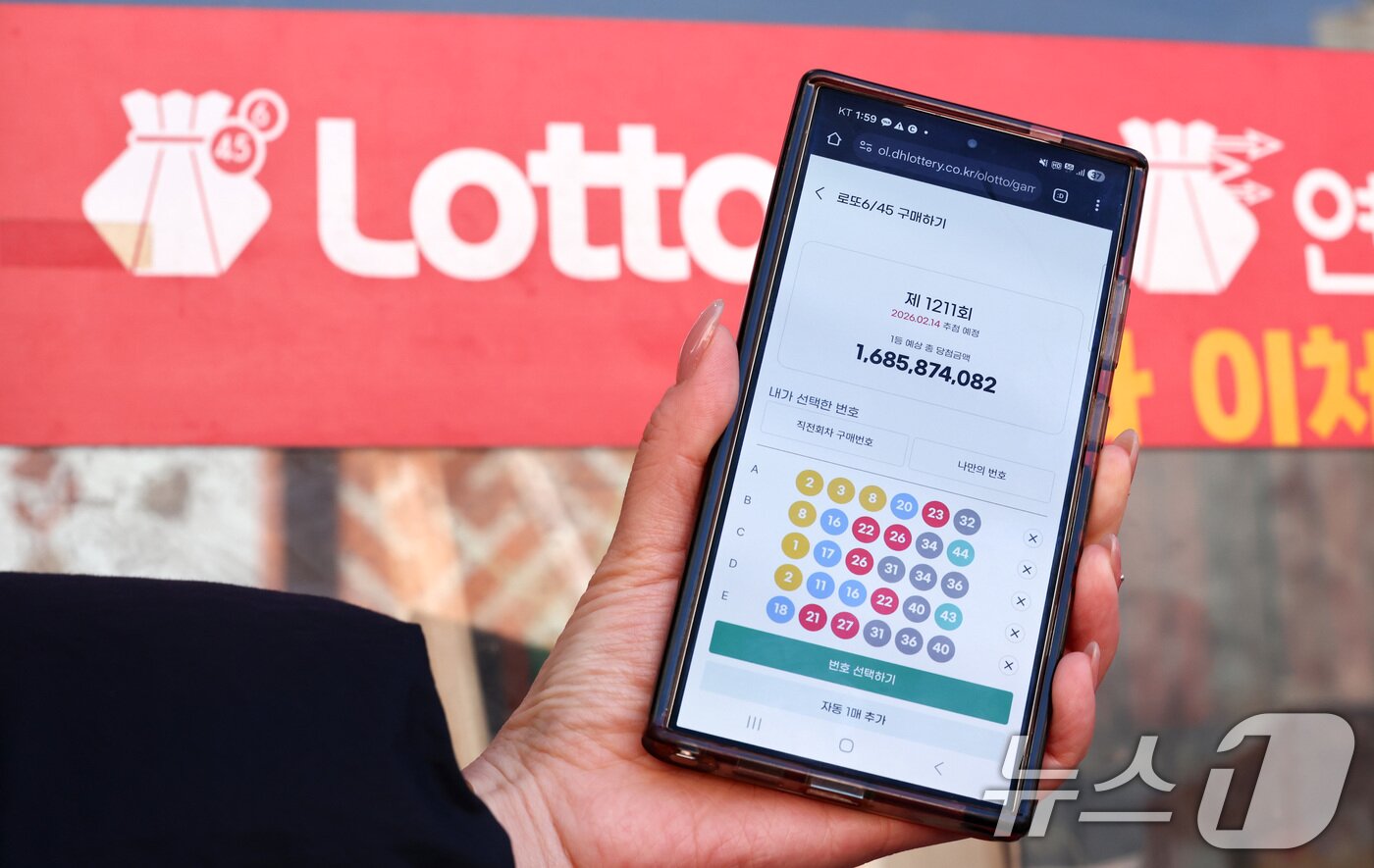 본문 이미지 - 모바일 로또 판매가 시작된 9일 서울 시내의 한 복권 판매점 앞에서 시민이 휴대폰으로 로또를 구매하고 있다. 2026.2.9 ⓒ 뉴스1 최지환 기자