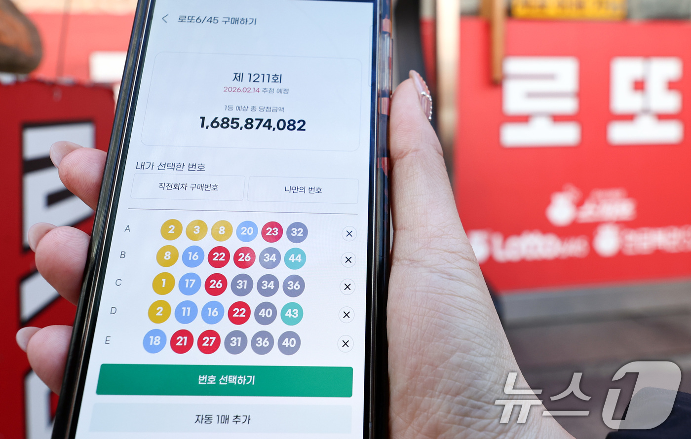(서울=뉴스1) 최지환 기자 = 모바일 로또 판매가 시작된 9일 서울 시내의 한 복권 판매점 앞에서 시민이 휴대폰으로 로또를 구매하고 있다.이용자는 모바일 동행복권 홈페이지에 가입 …