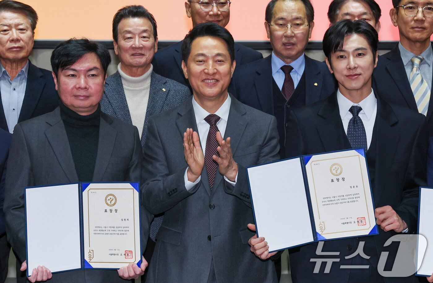 본문 이미지 - 오세훈 서울시장이 11일 오전 시청에서 열린 2026년 유공납세자 표창장 수여식에 참석해 가수 겸 배우 정윤호(유노윤호), 배우 임원희를 비롯한 유공납세자들에게 표창장을 수여한 뒤 기념 촬영을 하고 있다. 2026.3.11 ⓒ 뉴스1 안은나 기자