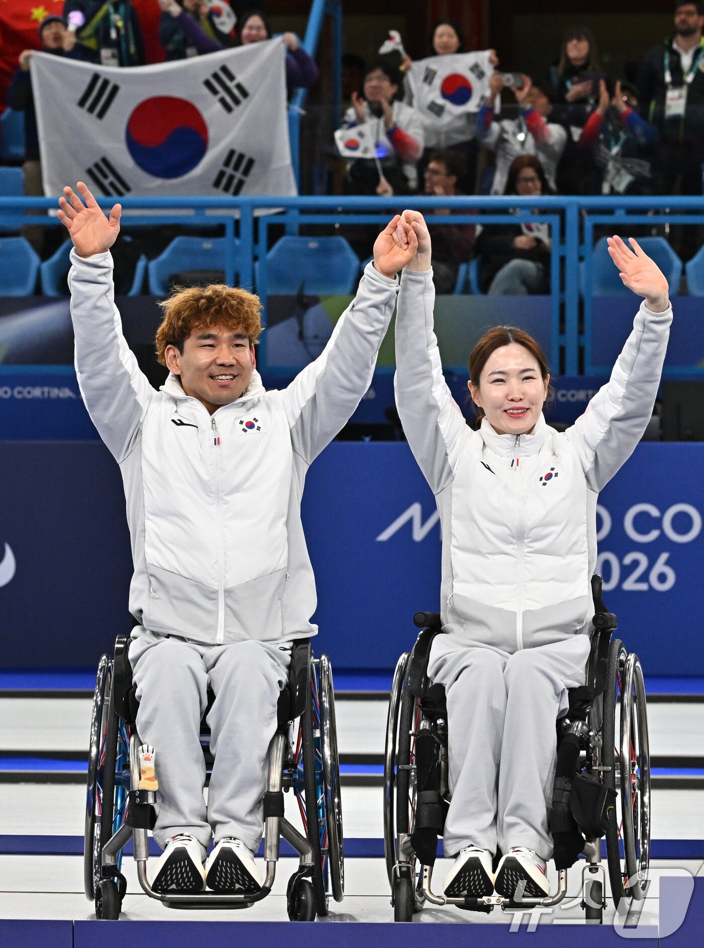 본문 이미지 - 휠체어컬링 백혜진(오른쪽)과 이용석이 11일(현지시간) 이탈리아 코르티나담페초 컬링 올림픽 스타디움에서 열린 2026 밀라노 코르티나 패럴림픽 휠체어컬링 믹스더블에서 은메달을 차지한 뒤 환호하는 관중들에게 인사를 하고 있다. 2026.3.12 ⓒ 뉴스1 사진공동취재단