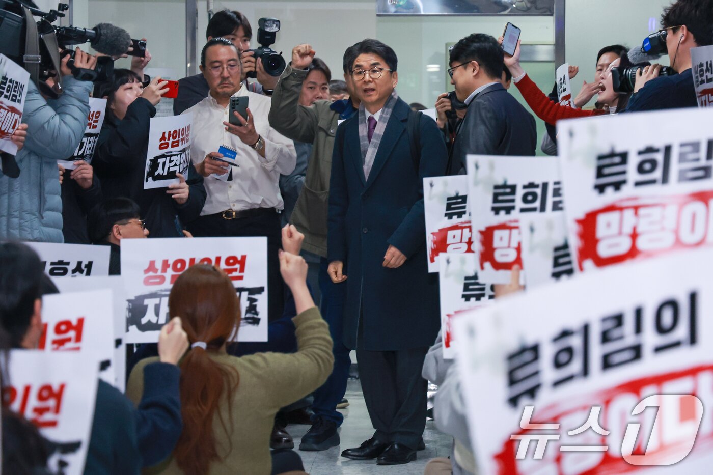 본문 이미지 - 전국언론노동조합 조합원들이 12일 오후 서울 양천구 방송미디어통신심의위원회에서 2026년 제1차 방미심위 정기 회의를 앞두고 윤석열 정부 방심위원이었던 김우석 상임위원 임명 철회를 촉구하며 구호를 외치는 가운데 김 위원이 회의장으로 향하고 있다. 2026.3.12 ⓒ 뉴스1 안은나 기자