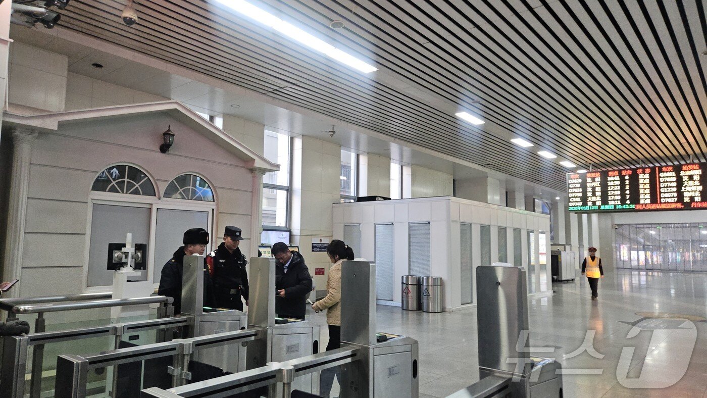 본문 이미지 - 12일 오후 중국 단둥역에 도착한 북중 여객열차 탑승객이 북한 여권을 제시한 후 출구를 나오고 있다.