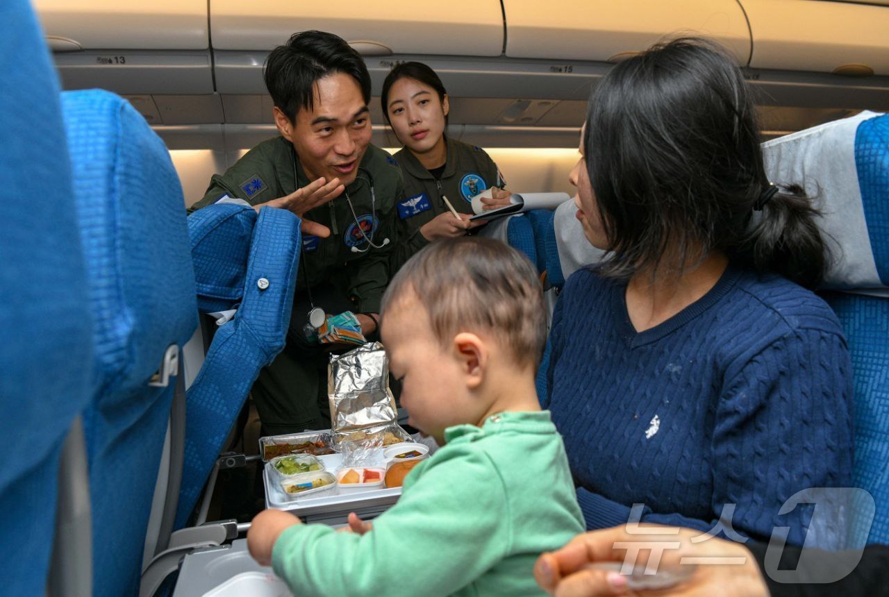 (서울=뉴스1) = 15일 사우디를 출발하는 공군 수송기(KC-330)에 탑승한 군의관이 감기 증세가 있는 어린아이를 살피고 있다. (국방부 제공. 재판매 및 DB 금지)  202 …