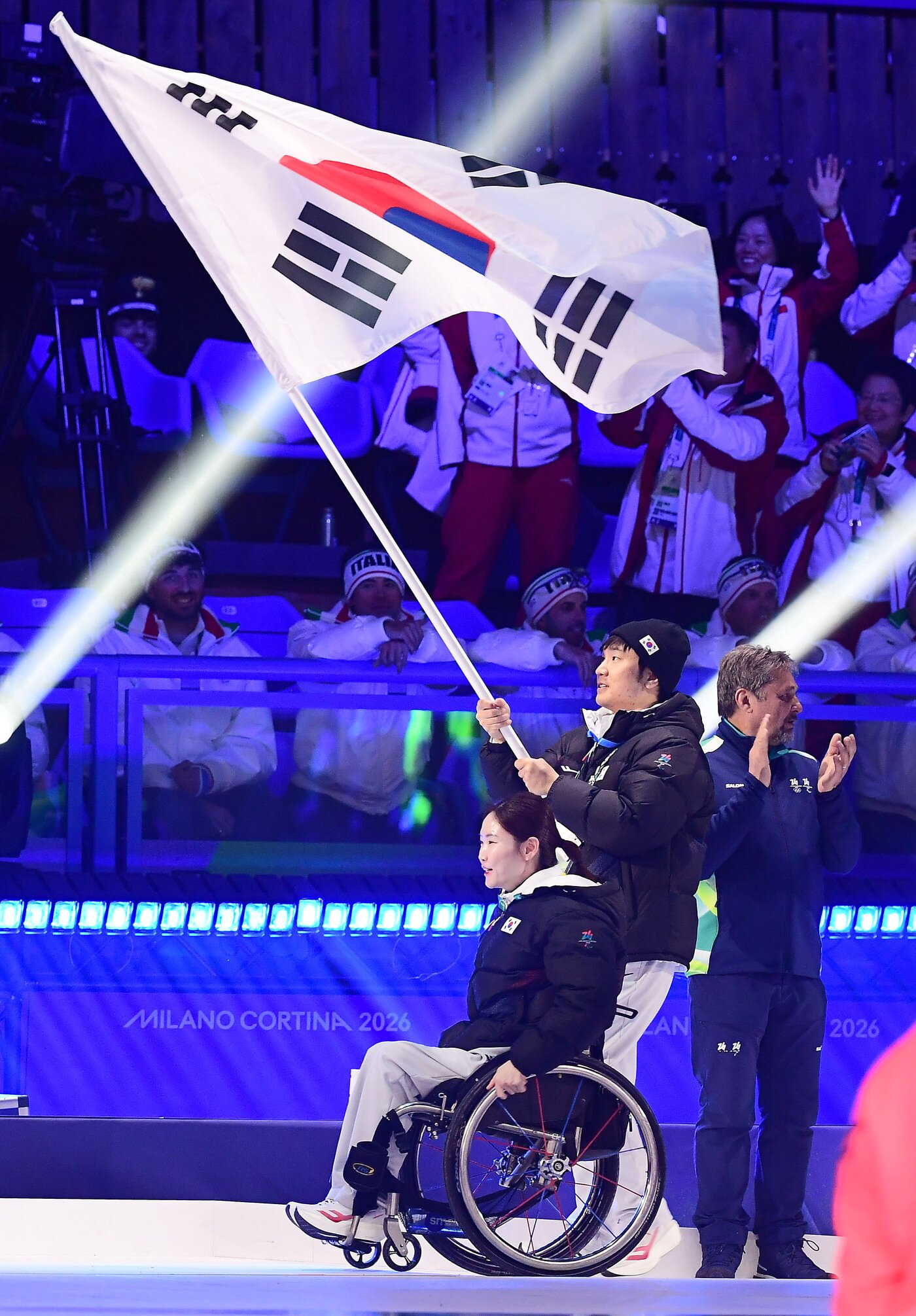 본문 이미지 - 한국 선수단 기수 이제혁과 백혜진이 16일(한국시간) 열린 2026 밀라노·코르티나담페초 동계패럴림픽 폐회식에서 태극기를 들고 입장하고 있다. (대한장애인체육회 제공)