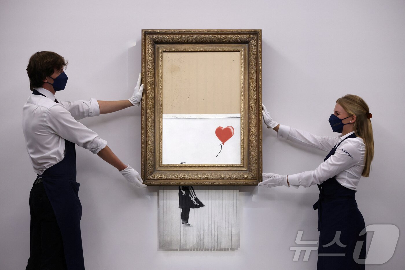 본문 이미지 - 뱅크시의 작품인 '풍선과 소녀'. 2018년 런던 소더비 경매에서 약 100만파운드(당시 약 16억원)에 낙찰된 직후 경매장에서 원격 조종을 통해 스스로 파쇄되는 충격적인 장면을 연출하며 더욱 유명해졌다. 이로 인해 '사랑은 쓰레기통에'(Love is in the Bin)라는 새로운 이름도 붙었다. 이후 3년 뒤인 2021년 다시 경매에 나와 19배에 가까운 약 1900만파운드(약 300억원)에 낙찰됐다. ⓒ 로이터=뉴스1