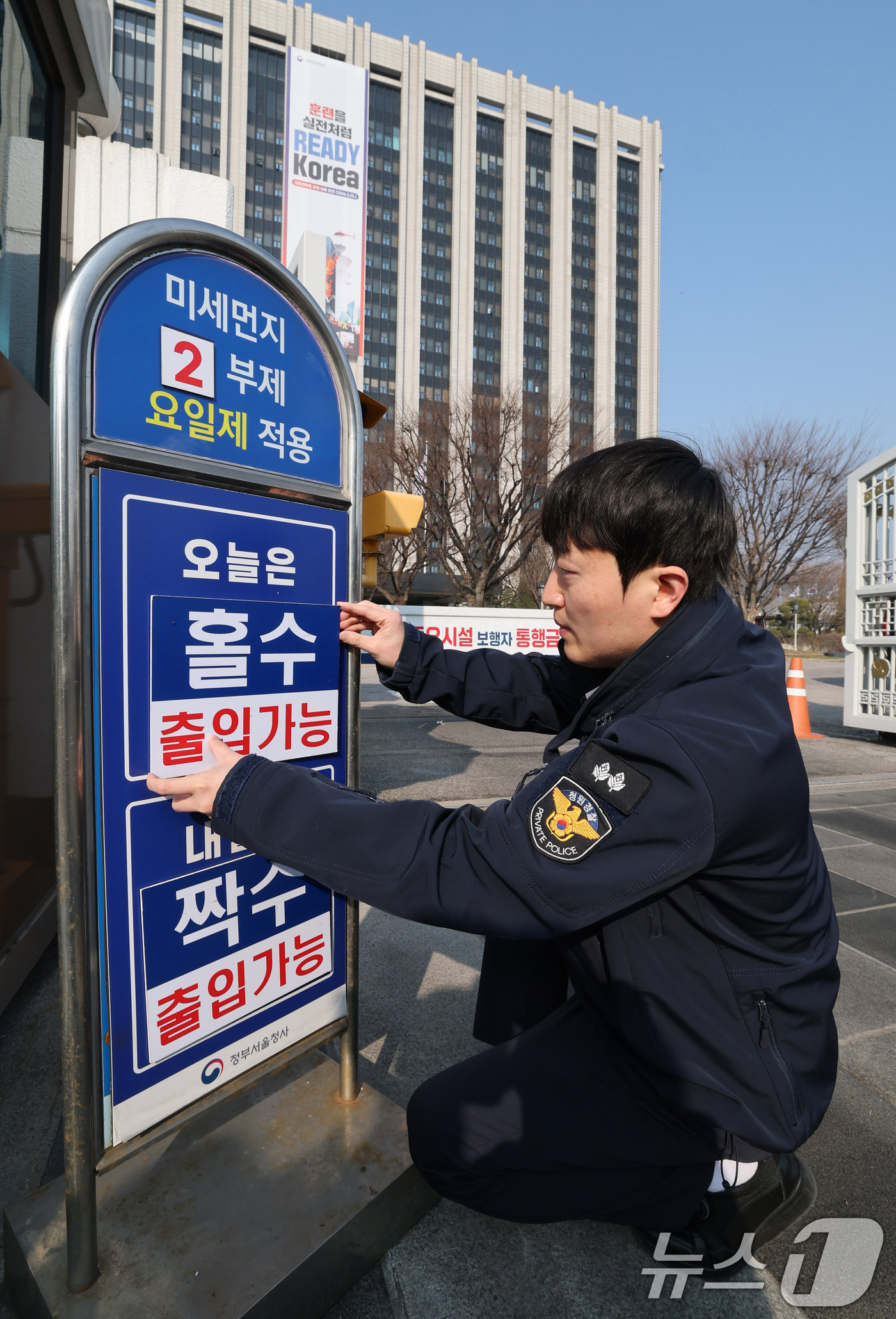 (서울=뉴스1) 임세영 기자 = 미세먼지 비상저감조치가 발령된 17일 오전 서울 종로구 정부서울청사에서 관계자가 입구에 고농도 미세먼지 비상저감조치에 따른 차량 2부제 실시 안내판 …