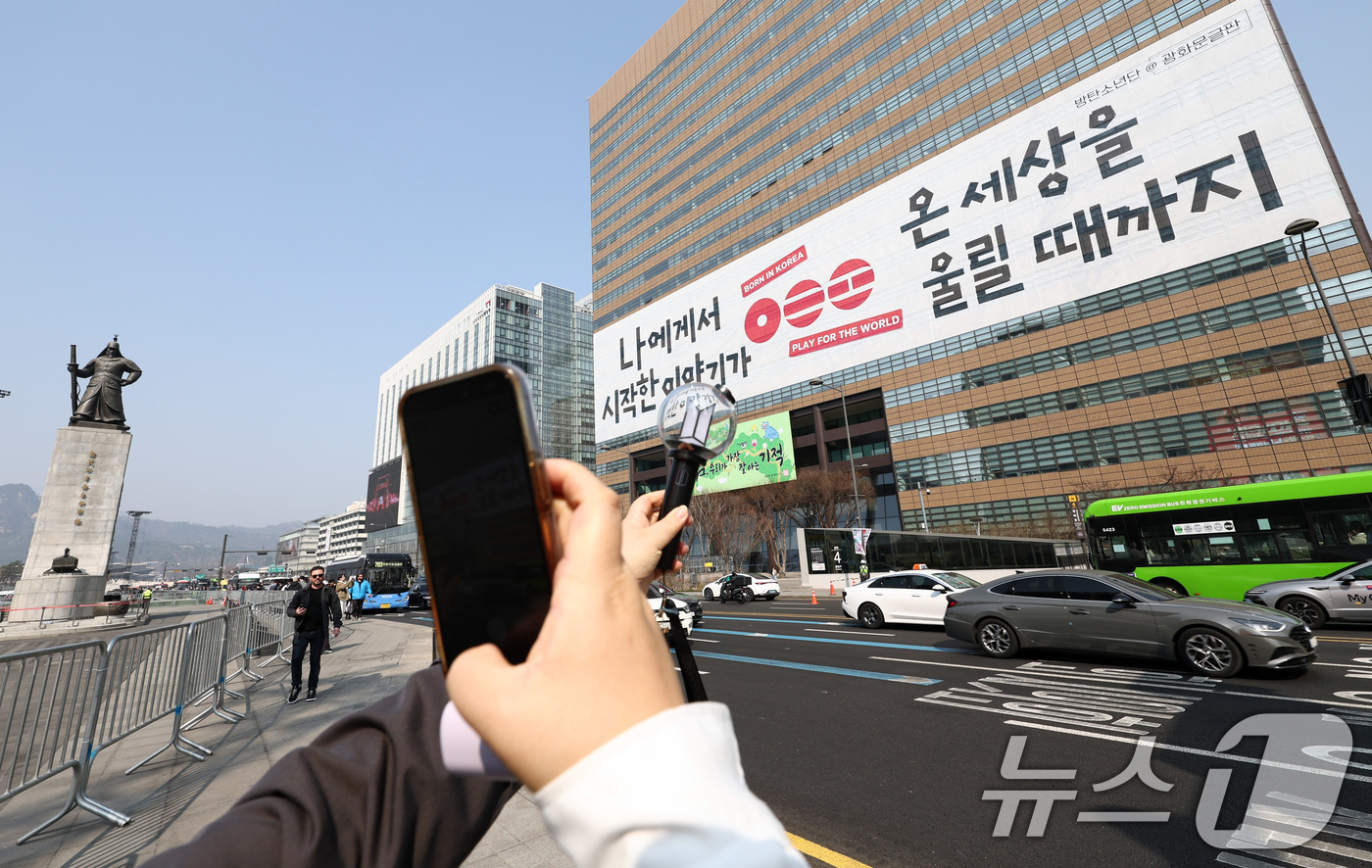 (서울=뉴스1) 최지환 기자 = 방탄소년단(BTS) 컴백 공연을 앞둔 17일 서울 종로구 광화문광장에서 한 팬이 교보생명빌딩 광화문글판에 걸린 BTS 컴백 문구를 배경으로 기념촬영 …