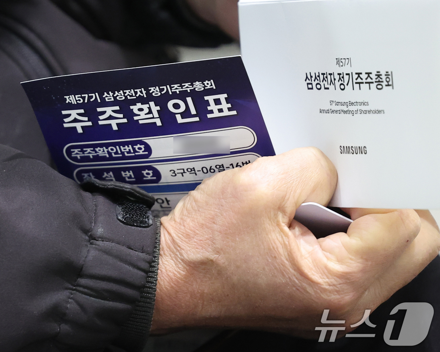 (수원=뉴스1) 김영운 기자 = 18일 오전 경기 수원시 영통구 수원컨벤션센터에서 열린 제57기 삼성전자 정기 주주총회에서 주주가 주주확인표를 들고 있다. (공동취재) 2026.3 …