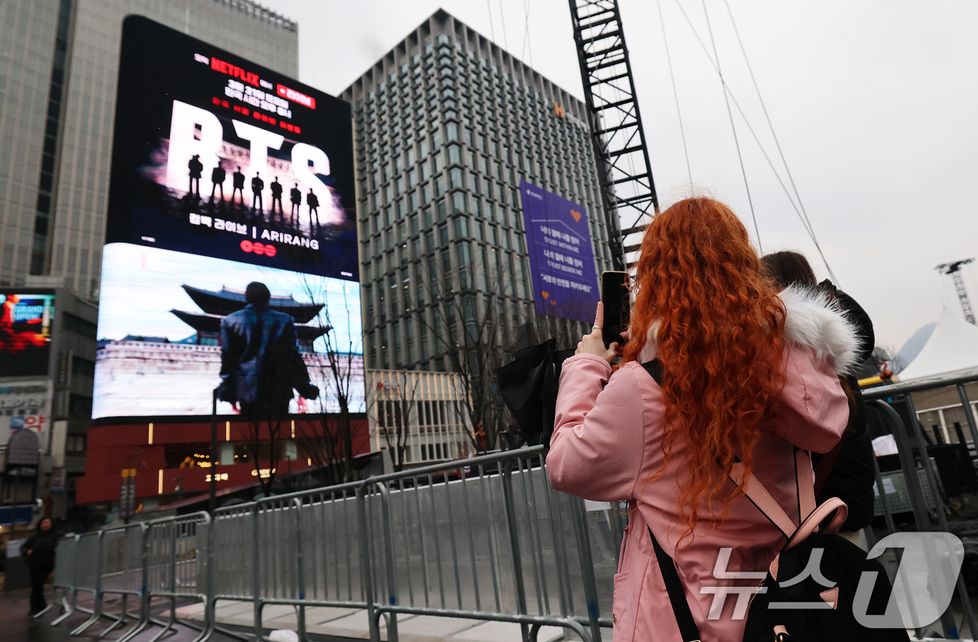(서울=뉴스1) 오대일 기자 = 방탄소년단(BTS) 완전체 컴백 공연을 사흘 앞둔 18일 서울 광화문광장에서 외국인 팬들이 컴백 공연을 알리는 전광판 광고를 스마트폰으로 촬영하고 …