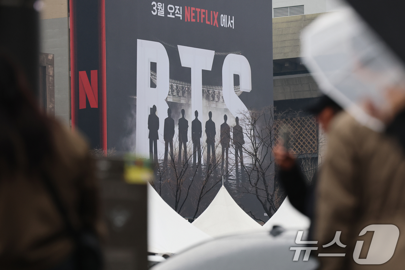 (서울=뉴스1) 오대일 기자 = 방탄소년단(BTS) 완전체 컴백 공연을 사흘 앞둔 18일 서울 광화문광장에서 외국인 팬들이 컴백 공연을 알리는 전광판 광고를 스마트폰으로 촬영하고 …