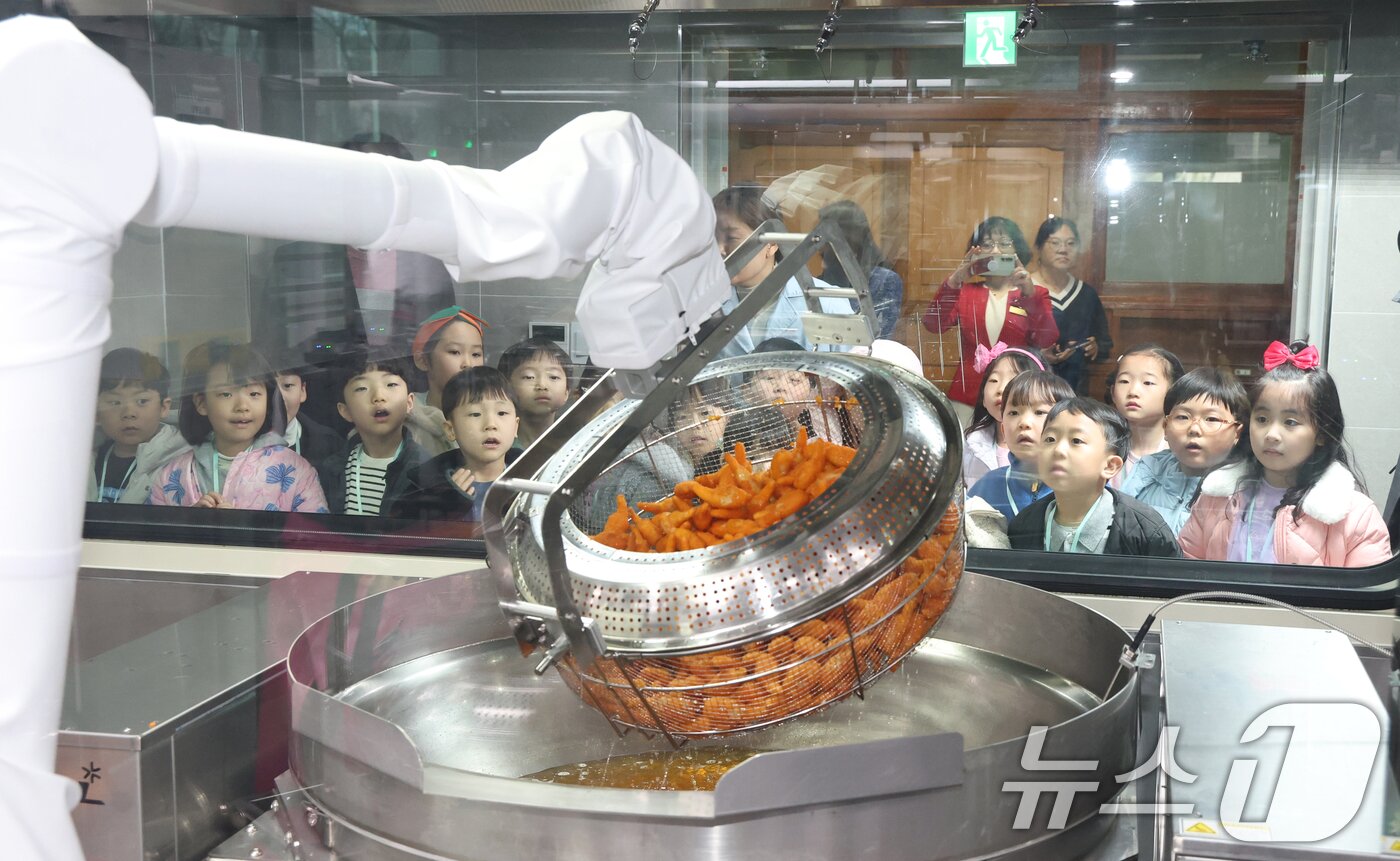 본문 이미지 - 18일 경기 수원시 장안구 대평초등학교 내 위치한 거점형 학교급식 튀김 지원실에서 1학년 학생들이 튀김 조리 로봇이 직접 가동되는 현장을 보고 있다.  2026.3.18 ⓒ 뉴스1 김영운 기자