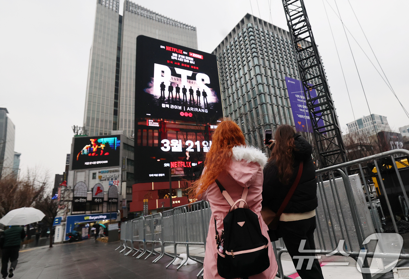 (서울=뉴스1) 오대일 기자 = 방탄소년단(BTS) 완전체 컴백 공연을 사흘 앞둔 18일 서울 광화문광장에서 외국인 팬들이 컴백 공연을 알리는 전광판 광고를 스마트폰으로 촬영하고 …
