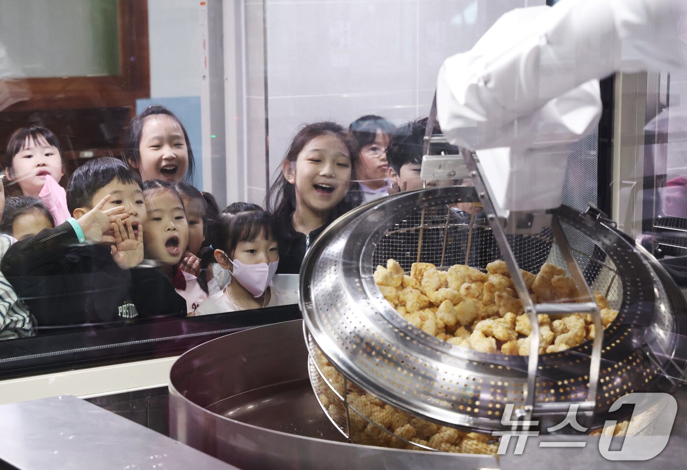본문 이미지 - 18일 경기 수원시 장안구 대평초등학교 내 위치한 거점형 학교급식 튀김 지원실에서 1학년 학생들이 튀김 조리 로봇이 직접 가동되는 현장을 보고 있다.  2026.3.18 ⓒ 뉴스1 김영운 기자