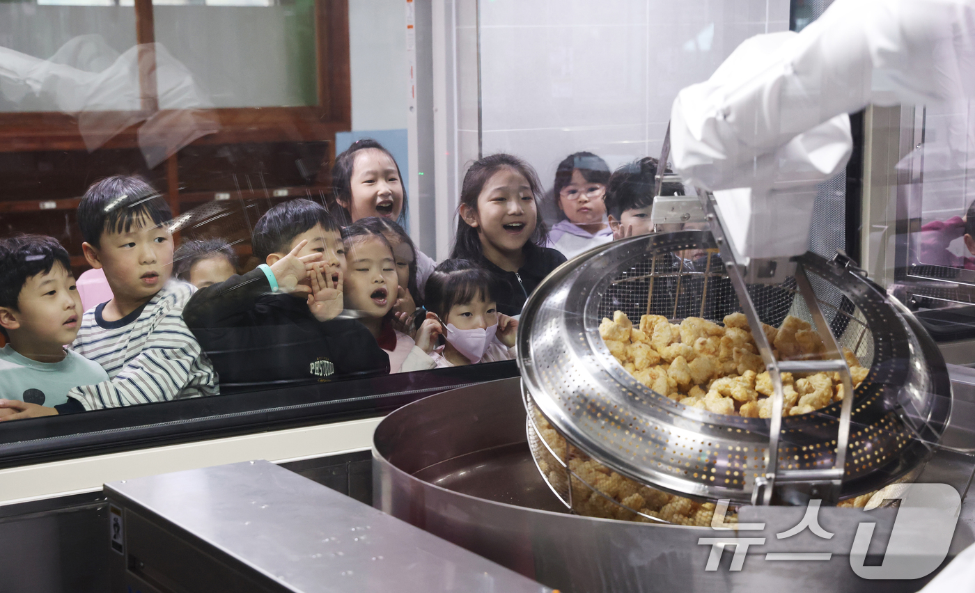 (수원=뉴스1) 김영운 기자 = 18일 경기 수원시 장안구 대평초등학교 내 위치한 거점형 학교급식 튀김 지원실에서 1학년 학생들이 튀김 조리 로봇이 직접 가동되는 현장을 보고 있다 …