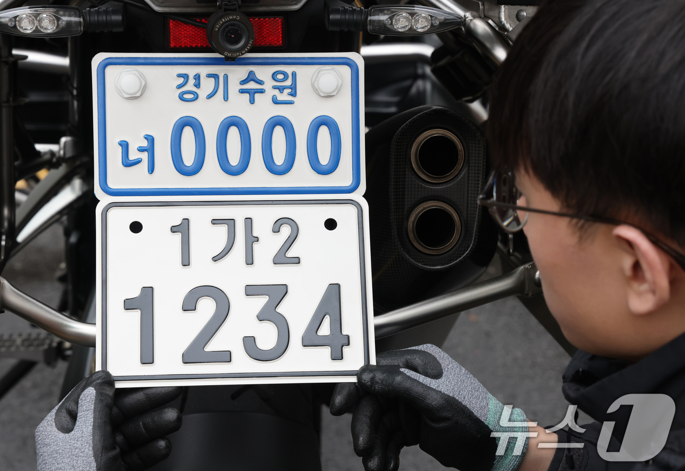 (수원=뉴스1) 김영운 기자 = 이륜자동차 전국 번호판 제도 시행을 이틀 앞둔 18일 경기 수원시 권선구 수원도시공사 번호판제작소에서 관계자가 번호판 교체 시연을을 하고 있다.새롭 …