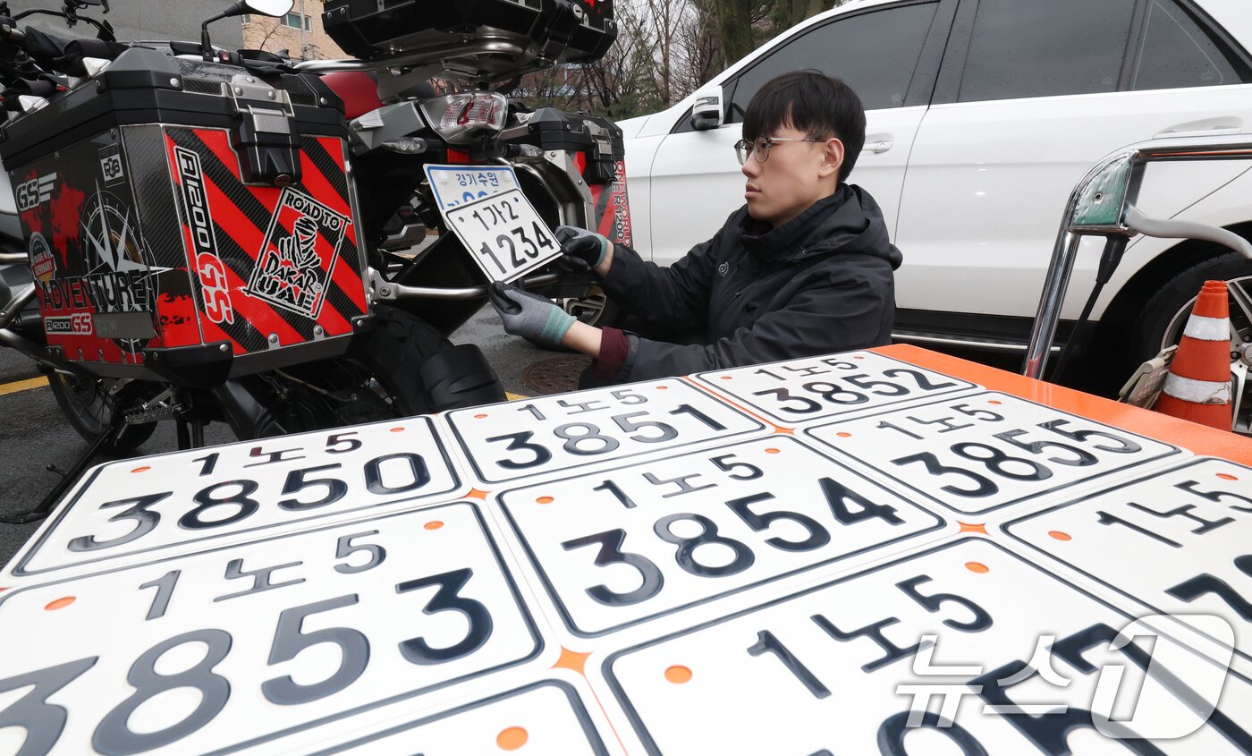 본문 이미지 - 이륜자동차 전국 번호판 제도 시행을 이틀 앞둔 18일 경기 수원시 권선구 수원도시공사 번호판제작소에서 관계자가 번호판 교체 시연을을 하고 있다.  ⓒ 뉴스1 김영운 기자