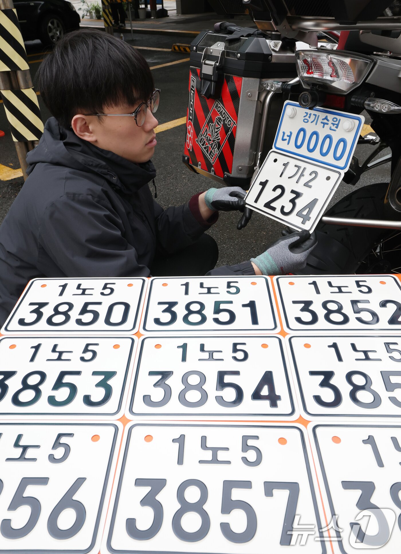 본문 이미지 - 이륜자동차 전국 번호판 제도 시행을 이틀 앞둔 18일 경기 수원시 권선구 수원도시공사 번호판제작소에서 관계자가 번호판 교체 시연을을 하고 있다.  ⓒ 뉴스1 김영운 기자