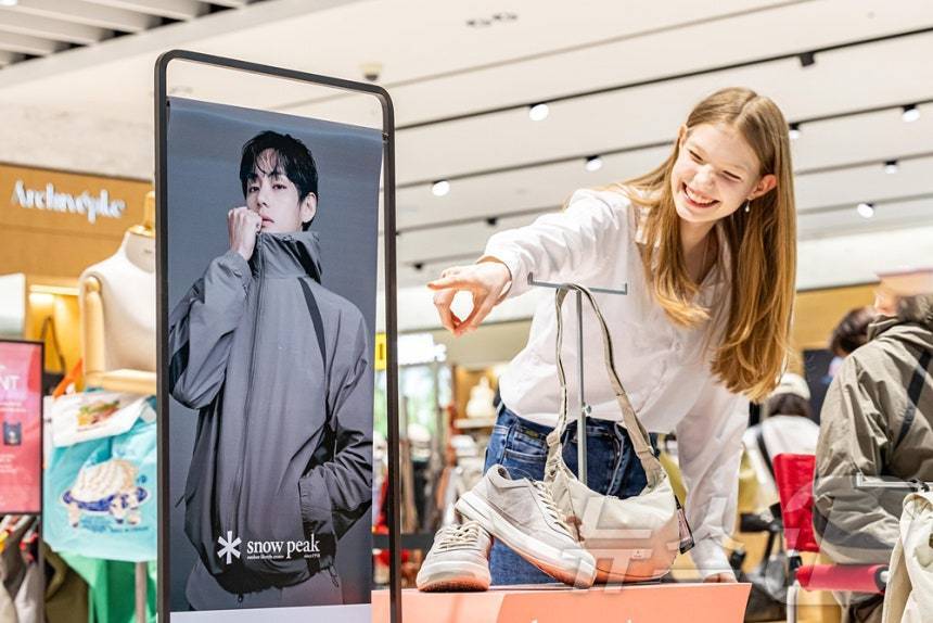 본문 이미지 - 사진은 외국인 모델이 신세계면세점 명동점 K-패션 매장 앞에서 방탄소년단 멤버 뷔의 화보사진을 보는 모습. (신세계면세점 제공. 재판매 및 DB 금지) 2026.3.11 ⓒ 뉴스1