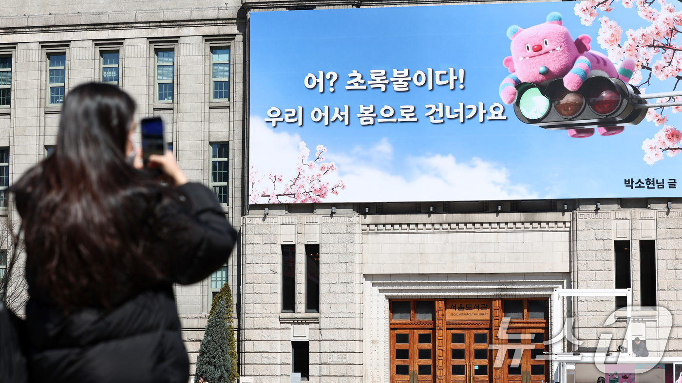 (서울=뉴스1) 최지환 기자 = 19일 서울 중구 서울도서관 외벽에 ‘어? 초록불이다! 우리, 어서 봄으로 건너가요’라는 문구가 적힌 서울꿈새김판이 걸려 있다. 2026.3.19/ …