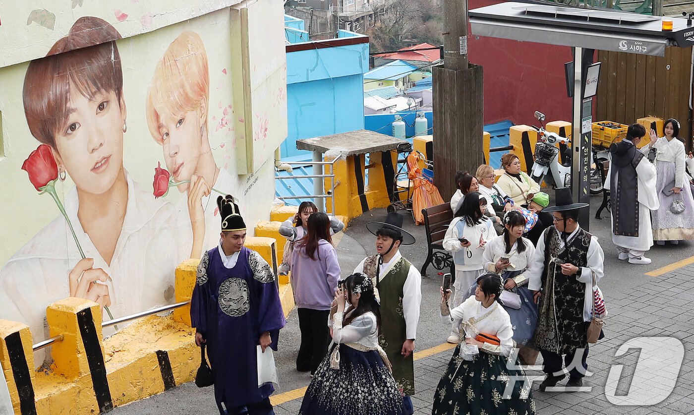 본문 이미지 -  부산 서구 감천문화마을에서 외국인 관광객들이 부산이 고향인 BTS 멤버 정국·지민이 그려진 대형 벽화를 배경으로 기념촬영을 하고 있다. 2026.3.19 ⓒ 뉴스1 윤일지 기자