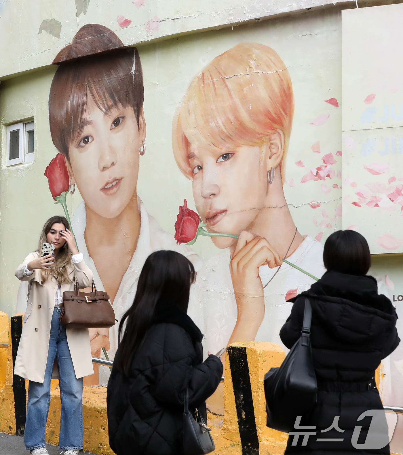 (부산=뉴스1) 윤일지 기자 = 방탄소년단(BTS) 컴백 공연을 이틀 앞둔 19일 부산 서구 감천문화마을에서 외국인 관광객들이 부산이 고향인 BTS 멤버 정국·지민이 그려진 대형 …