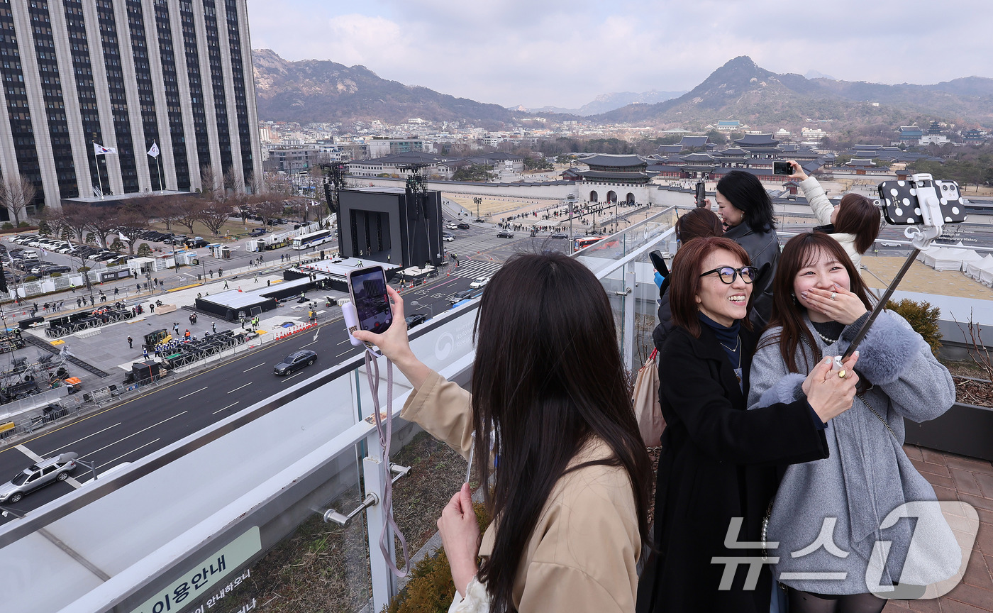 (서울=뉴스1) 박지혜 기자 = 방탄소년단(BTS) 완전체 컴백 공연을 하루 앞둔 20일 서울 광화문광장 인근에서 아미(ARMY·팬덤명)들이 공연장을 배경으로 기념 사진을 찍고 있 …