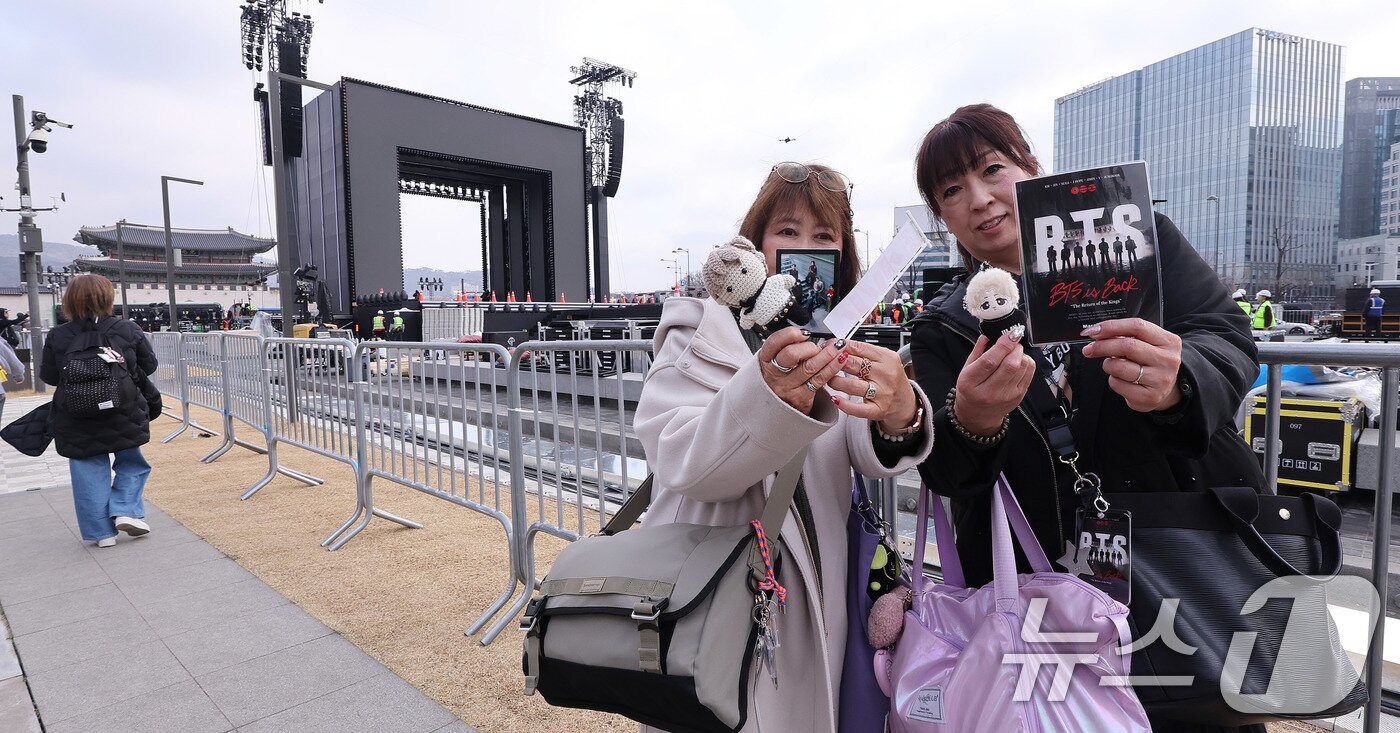 본문 이미지 - 방탄소년단(BTS) 완전체 컴백 공연을 하루 앞둔 20일 서울 광화문광장 공연장 앞에 일본에서 온 아미(ARMY·팬덤명)들이 굿즈를 들어보이고 있다. 2026.3.20 ⓒ 뉴스1 박지혜 기자