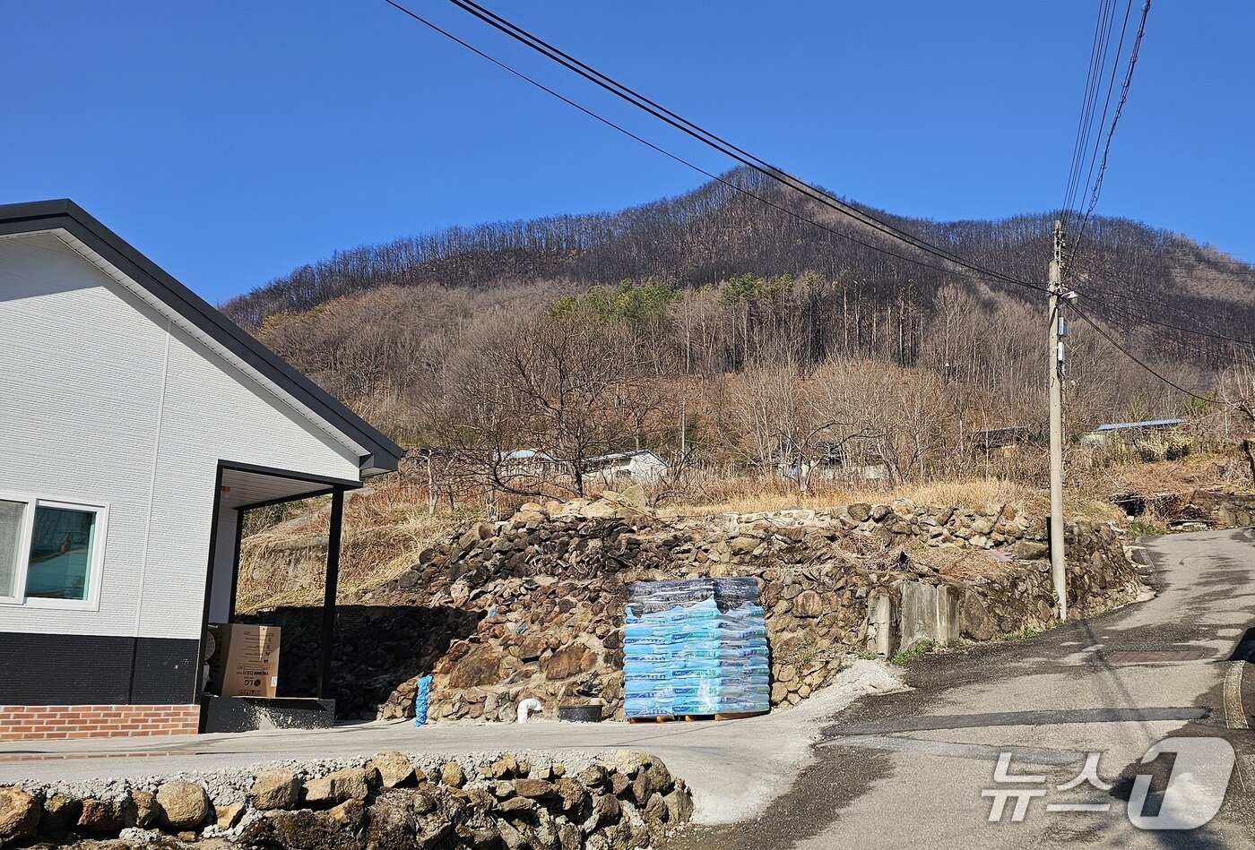 본문 이미지 - 산청군 시천면 외공마을의 신축 주택과 산불 흔적이 남아 있는 마을 뒷산. 2026.3.21/뉴스1 한송학기자