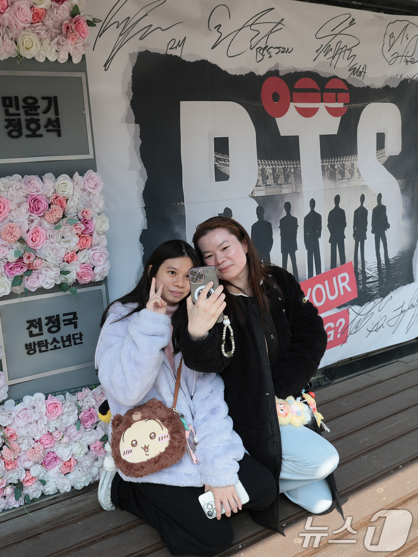 (서울=뉴스1) 권현진 기자 = 그룹 방탄소년단(BTS)의 광화문 공연을 앞둔 20일 서울 용산구 하이브 인근에서 팬들이 멤버들 혁수막 앞에서 기념 촬영을 하고 있다. 2026.3 …