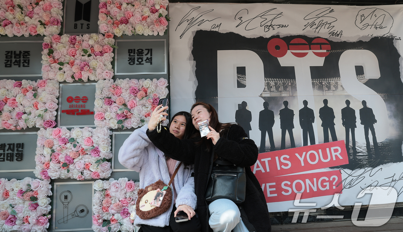 (서울=뉴스1) 권현진 기자 = 그룹 방탄소년단(BTS)의 광화문 공연을 앞둔 20일 서울 용산구 하이브 인근에서 팬들이 멤버들 혁수막 앞에서 기념 촬영을 하고 있다. 2026.3 …
