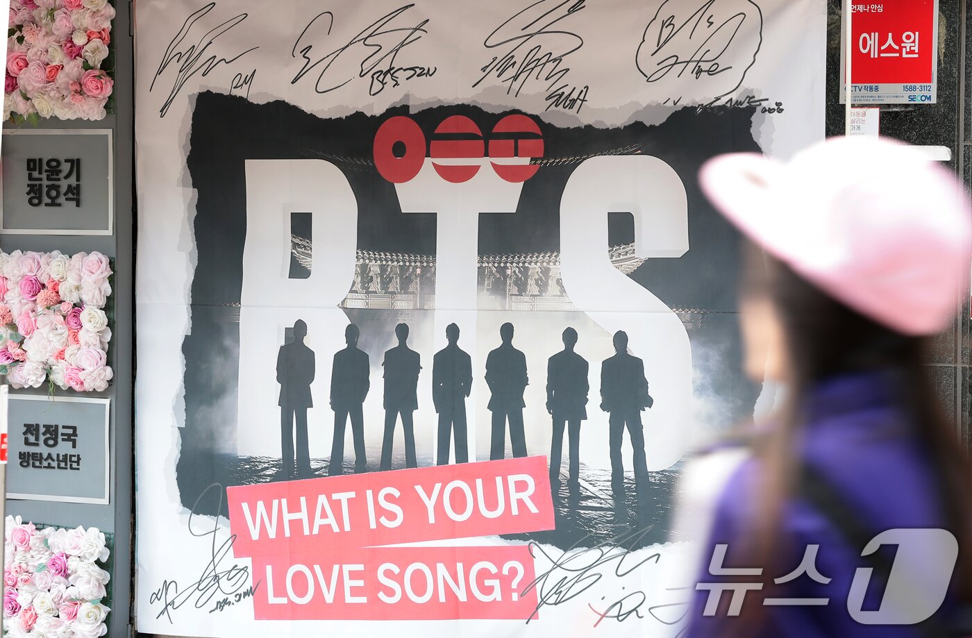 본문 이미지 - 그룹 방탄소년단(BTS)의 광화문 공연을 앞둔 20일 서울 용산구 하이브 인근에서 팬들이 멤버들 혁수막 앞을 지나가고 있다. 2026.3.20 ⓒ 뉴스1 권현진 기자