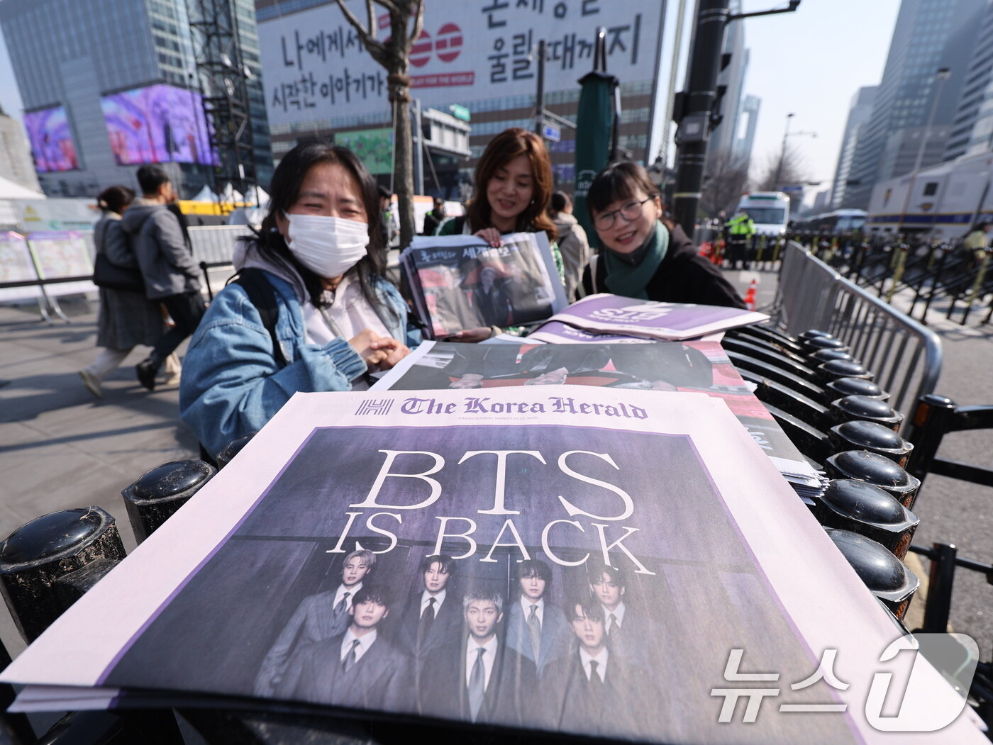 본문 이미지 - 방탄소년단(BTS) 컴백 공연일인 21일 오전 서울 광화문광장에서 외국인 관광객이 주요 일간지들이 발행한 BTS 관련 호외를 받고 있다. 2026.3.21 ⓒ 뉴스1 박지혜 기자