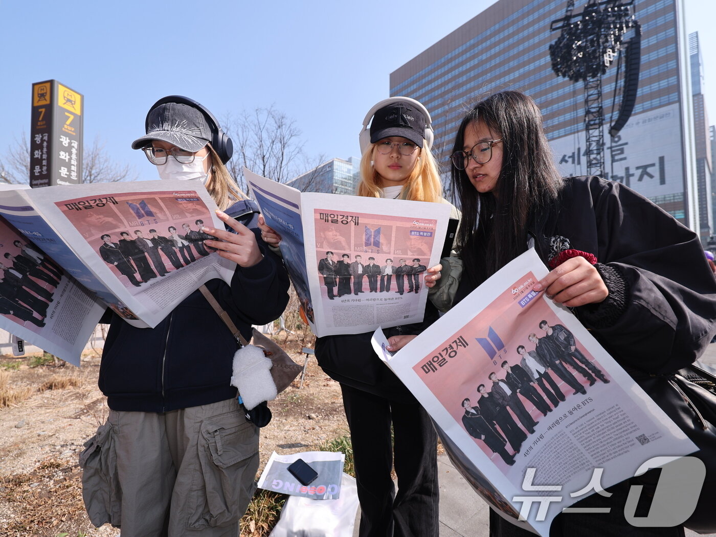 본문 이미지 - 방탄소년단(BTS) 컴백 공연일인 21일 서울 종로구 광화문광장에서 외국인 관광객들이 주요 일간지들이 발행한 BTS 관련 특별판을 보고 있다. 2026.3.21 ⓒ 뉴스1 박지혜 기자