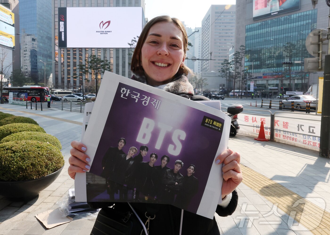 본문 이미지 - 방탄소년단(BTS) 컴백 공연일인 21일 오전 서울 을지로입구역에서 독일인 관광객이 주요 일간지들이 발행한 BTS 특별판을 들어보이고 있다. 2026.3.21 ⓒ 뉴스1 김진환 기자