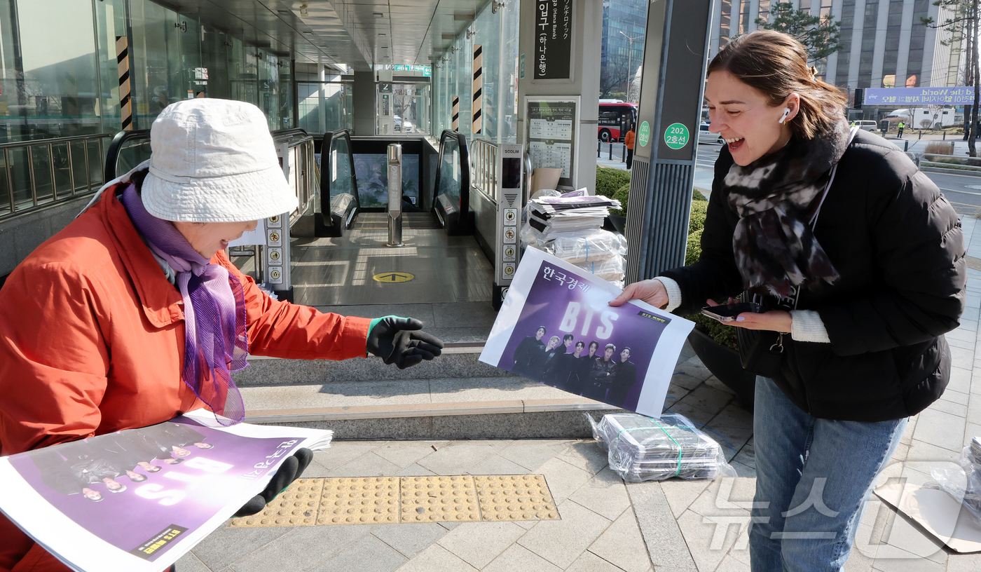 (서울=뉴스1) 김진환 기자 = 방탄소년단(BTS) 컴백 공연일인 21일 오전 서울 을지로입구역에서 독일인 관광객이 주요 일간지들이 발행한 BTS 특별판을 받고 있다. 2026.3 …