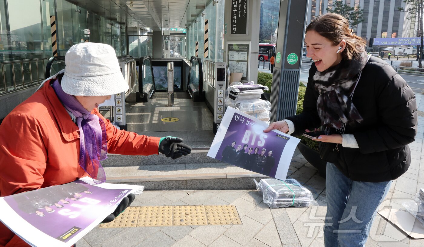 본문 이미지 - 방탄소년단(BTS) 완전체 컴백 공연을 앞둔 21일 오전 서울 을지로입구역에서 독일인 관광객이 한국경제신문의 BTS 특별판 호외를 받고 있다. 2026.3.21 ⓒ 뉴스1 김진환 기자