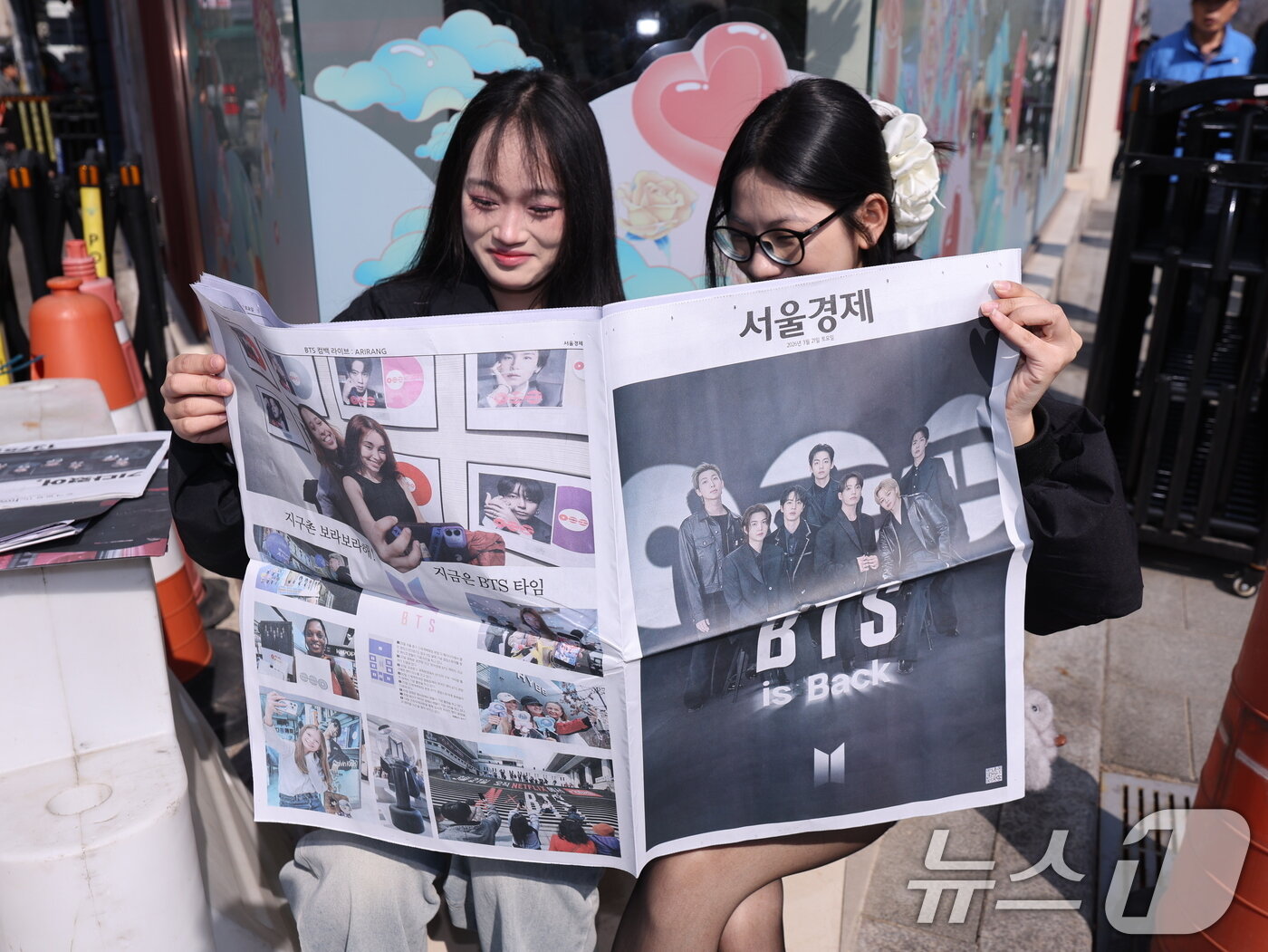 본문 이미지 - 방탄소년단(BTS) 컴백 공연일인 21일 오전 서울 광화문광장에서 일본인 관광객들이 주요 일간지들이 발행한 BTS 특별판을 보고 있다. 2026.3.21 ⓒ 뉴스1 박지혜 기자