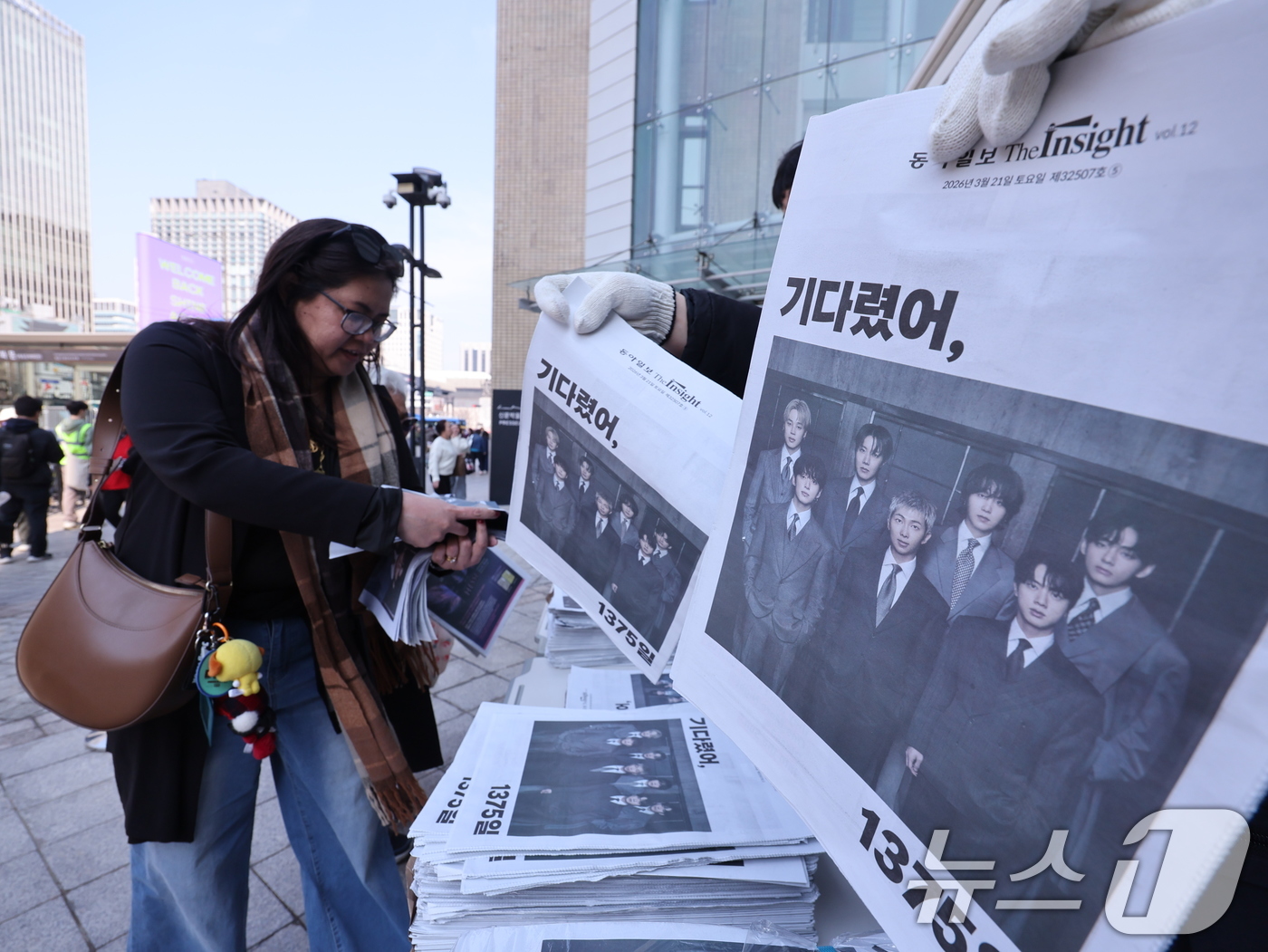 (서울=뉴스1) 박지혜 기자 = 방탄소년단(BTS) 컴백 공연일인 21일 오전 서울 광화문광장에서 외국인 관광객이 주요 일간지들이 발행한 BTS 관련 호외를 받고 있다. 2026. …