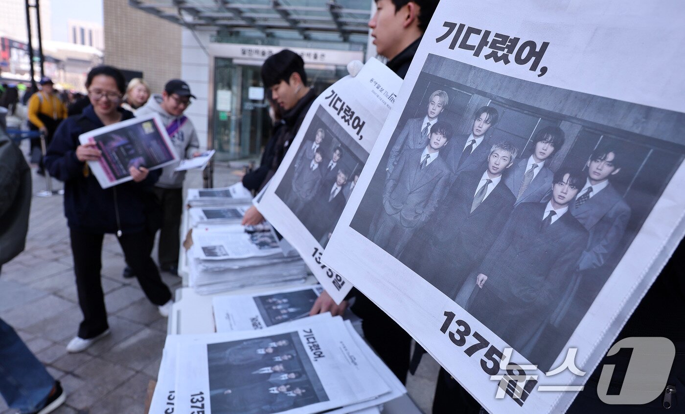 본문 이미지 - 방탄소년단(BTS) 컴백 공연일인 21일 오전 서울 광화문광장에서 외국인 관광객이 일간지들이 발행한 BTS 관련 특별판을 무료로 배포받고 있다. 2026.3.21 ⓒ 뉴스1 박지혜 기자