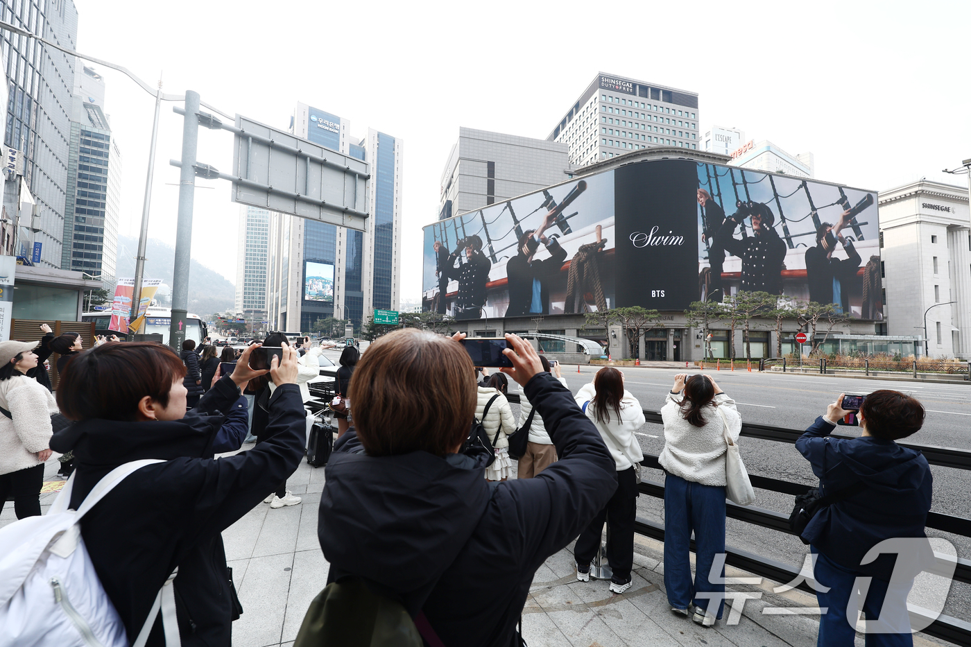 (서울=뉴스1) 김민지 기자 = 방탄소년단(BTS) 컴백 공연 다음 날인 22일 오전 서울 중구 신세계백화점 인근에서 방탄소년단의 팬클럽 ARMY가 SWIM 뮤직비디오를 보며 사진 …