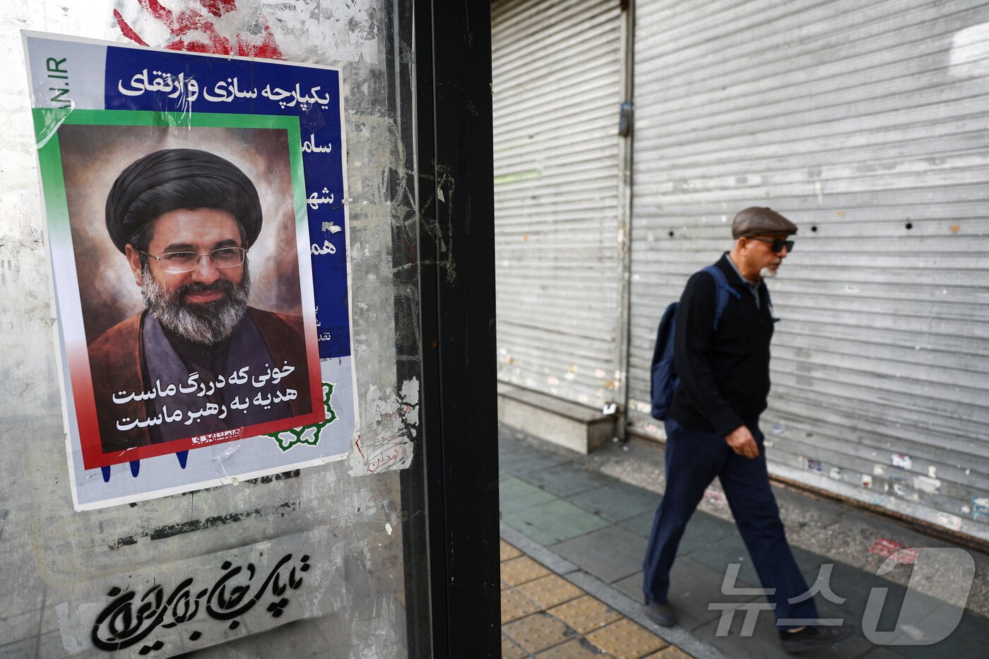 본문 이미지 - 22일 이란 수도 테헤란의 한 거리에 새 최고지도자인 모즈타바 하메네이의 포스터가 붙어 있다. 2026.3.22 ⓒ 로이터=뉴스1