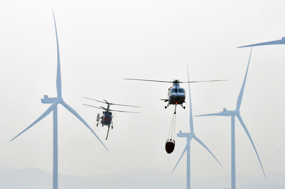 풍력발전기 사이로 비행하는 진화헬기