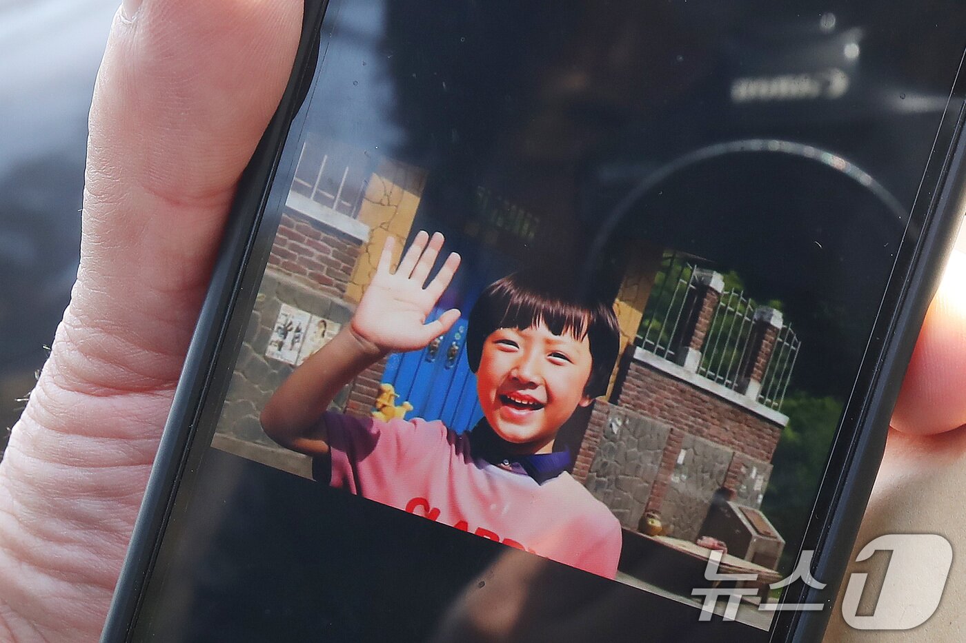 본문 이미지 - '개구리소년 35주기 추모제'에서 우철원 군(당시 13세) 아버지 우종우 씨(77)가 실종 당시 아들의 모습을 AI로 복원한 사진을 취재진에게 보여주고 있다. 2026.3.26 ⓒ 뉴스1 공정식 기자