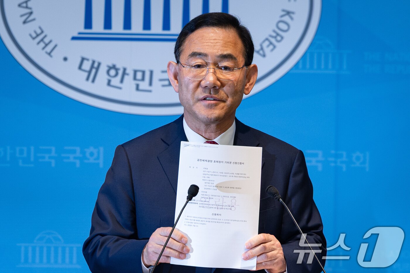 본문 이미지 - 주호영 국민의힘 의원이 26일 서울 여의도 국회 소통관에서 당 공천관리위원회의 대구시장 경선 공천 배제(컷오프)와 관련해 기자회견 중 공천배제결정 효력정지 가처분신청서를 들어보이고 있다. 앞서 국민의힘 공천관리위원회는 주 의원과 이진숙 전 방송통신위원장을 컷오프하고 나머지 6명의 후보로 예비경선을 치러 대구시장 후보를 확정하기로 했다. 주 의원은 이에 반발, 서울남부지법에 국민의힘을 상대로 공천배제결정 효력정지 가처분 신청을 냈다. 2026.3.26 ⓒ 뉴스1 유승관 기자