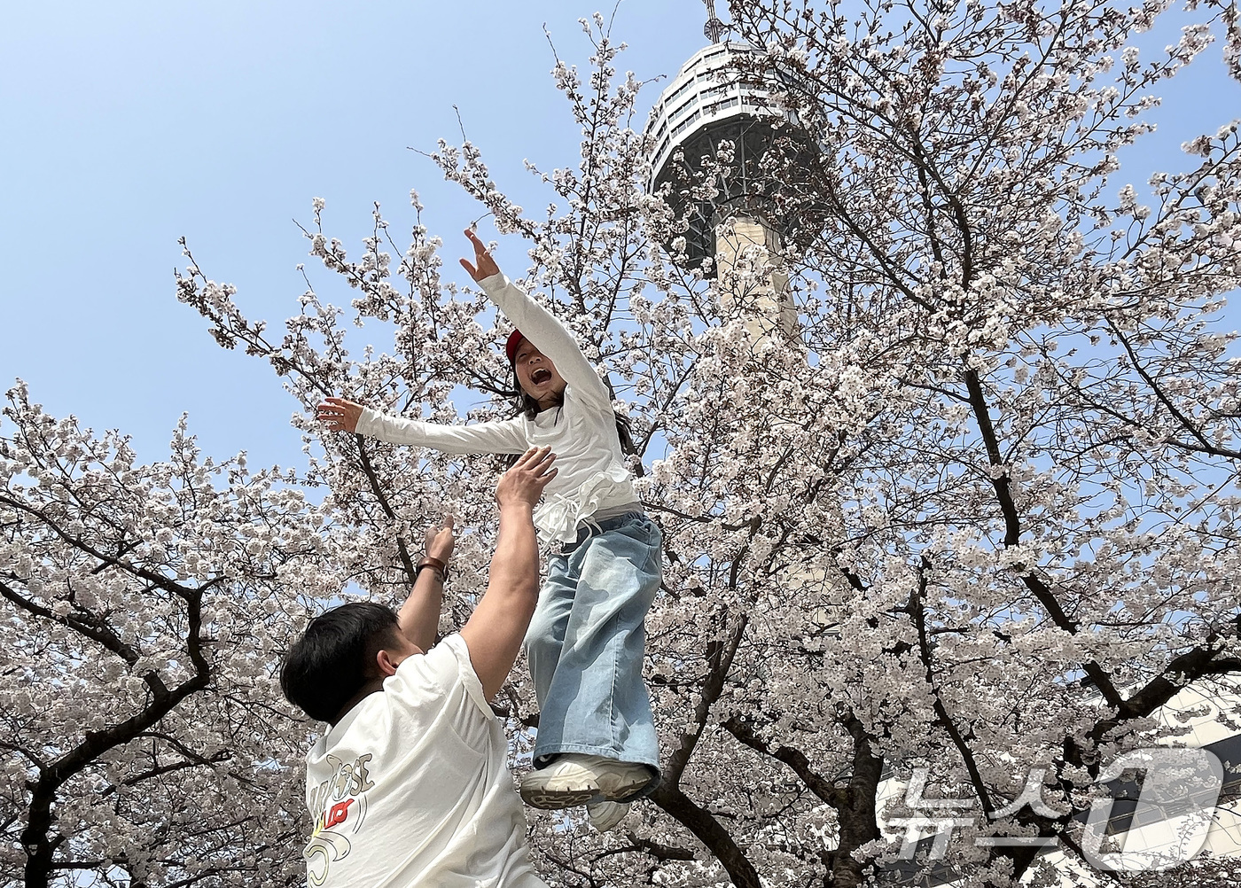 (대구=뉴스1) 공정식 기자 = 27일 대구 달서구 테마파크 이월드를 찾은 시민들이 곱게 핀 벚꽃을 배경으로 기념사진을 찍고 있다. 2026.3.27/뉴스1