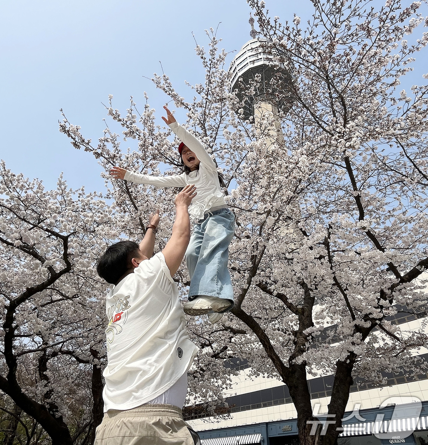 (대구=뉴스1) 공정식 기자 = 27일 대구 달서구 테마파크 이월드를 찾은 시민들이 곱게 핀 벚꽃을 배경으로 기념사진을 찍고 있다. 2026.3.27/뉴스1