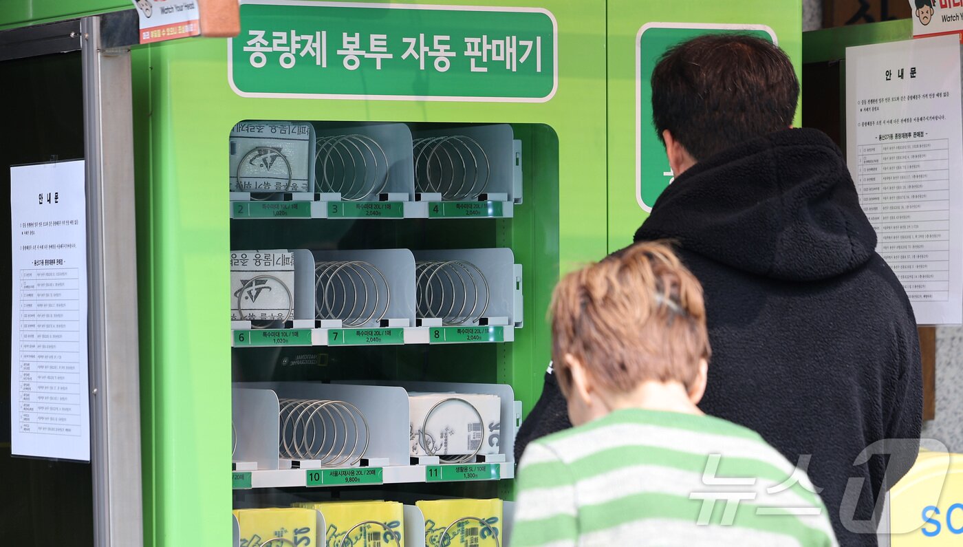본문 이미지 - 27일 서울 시내 한 주민센터에 설치된 종량제봉투 자동판매기에서 한 시민이 종량제 봉투를 구매하고 있다. 2026.3.27 ⓒ 뉴스1 김성진 기자