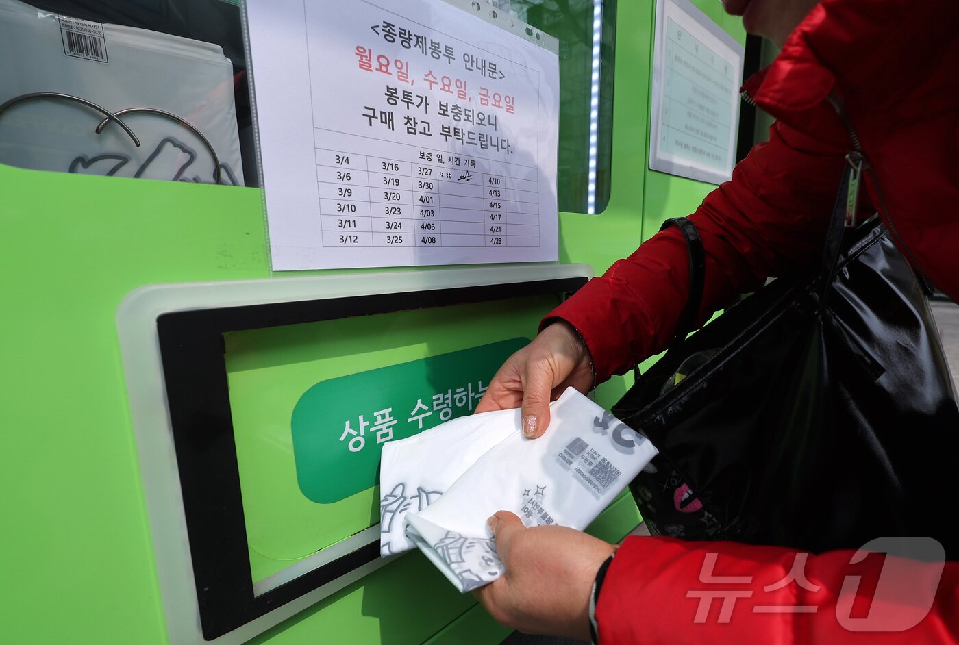 본문 이미지 - 27일 서울 시내 한 주민센터에 설치된 종량제봉투 자동판매기에서 한 시민이 종량제 봉투를 구매하고 있다. 2026.3.27 ⓒ 뉴스1 김성진 기자