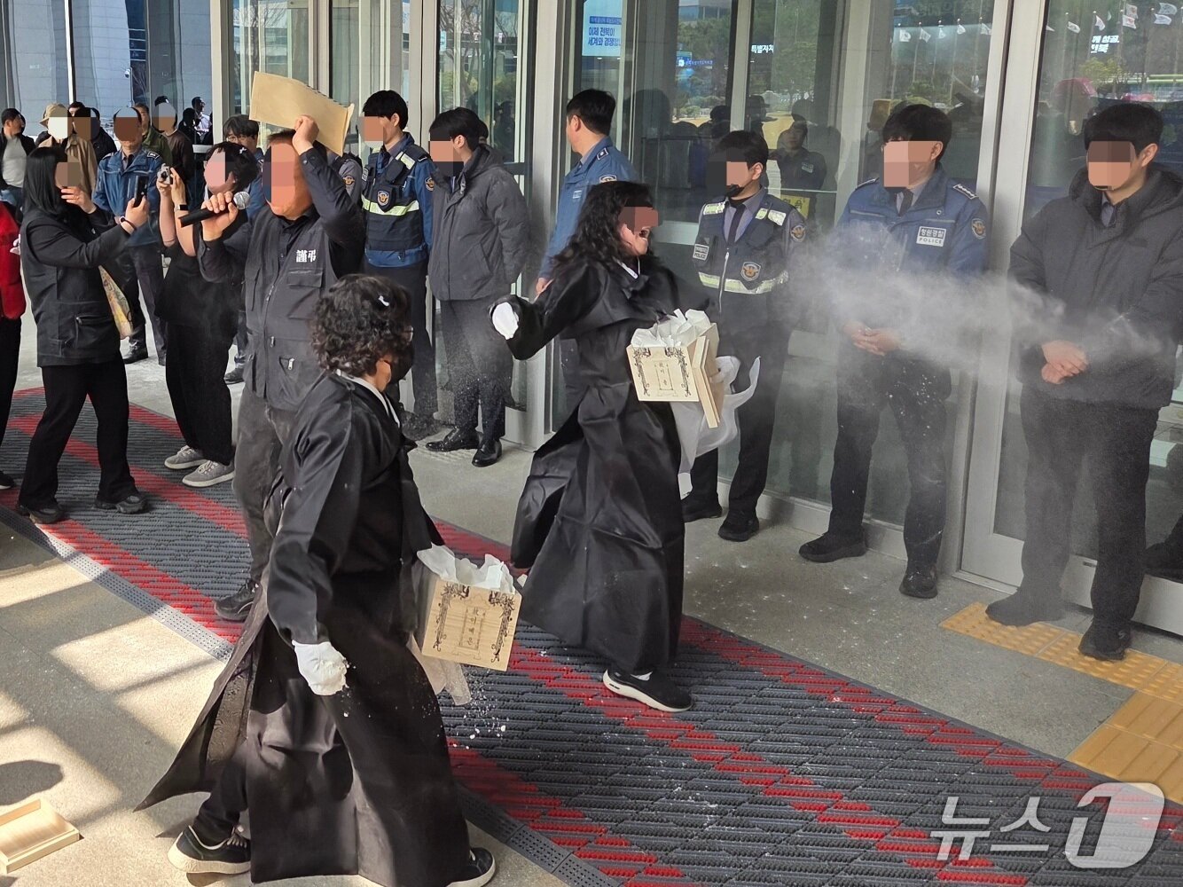 본문 이미지 - 27일 자임추모공원에 고인을 안치한 유가족이 유골함 안에 들어있던 밀가루를 전북도청 앞에 있는 청원경찰에게 뿌리고 있다.2026.3.27/뉴스1 문채연 기자